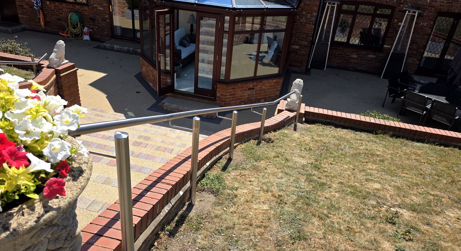 Brushed stainless steel handrail curved to a semi-helical garden wall, Beaconsfield